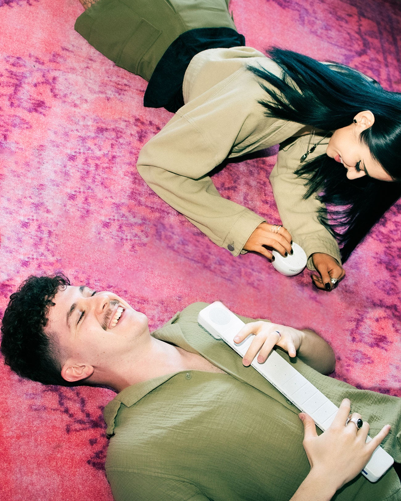 Couple lays on pink Carpet playing a white Orba and Chorda