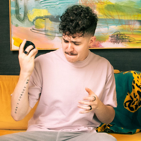 Person sitting on a couch playing the Orba by Artiphon, demonstrating various gestures including shaking.