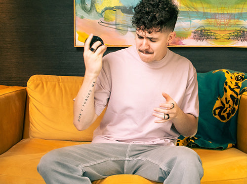 Person on couch using shake gesture to modify sounds on Orba handheld synthesizer