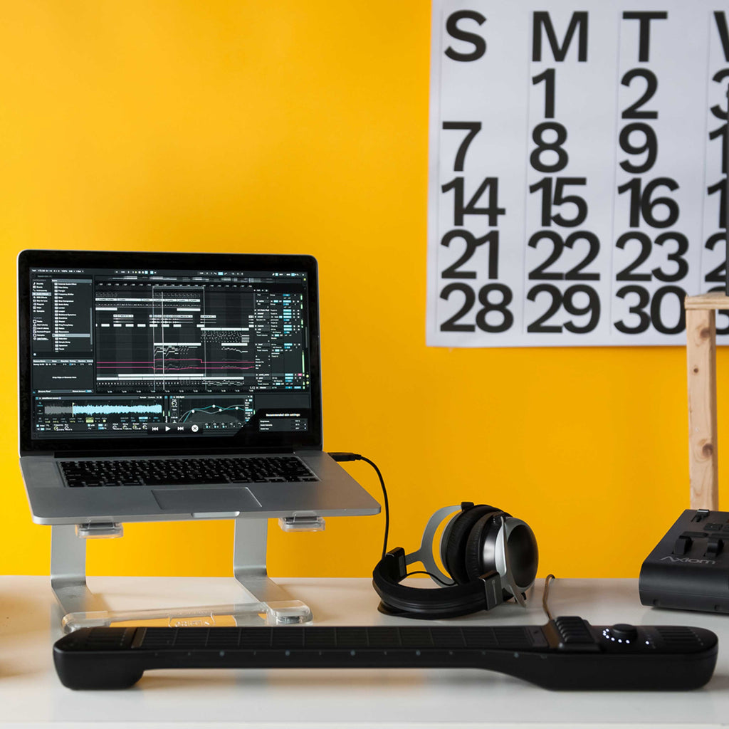 INSTRUMENT 1 on a desk plugged into a laptop with headphones and a yellow background.